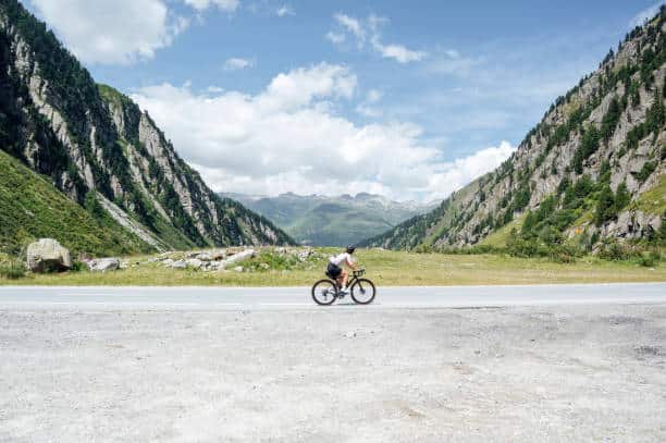 Cyclist enjoying a ride on a scenic mountain road, surrounded by stunning alpine landscapes