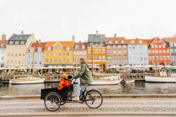 woman riding cargo bike with her kids