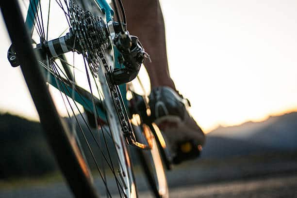 Closeup of a road cyclist riding towards sunset.