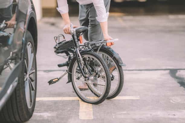 an asian chinese male white collar worker getting ready to work with his folding bicycle as transport commuting