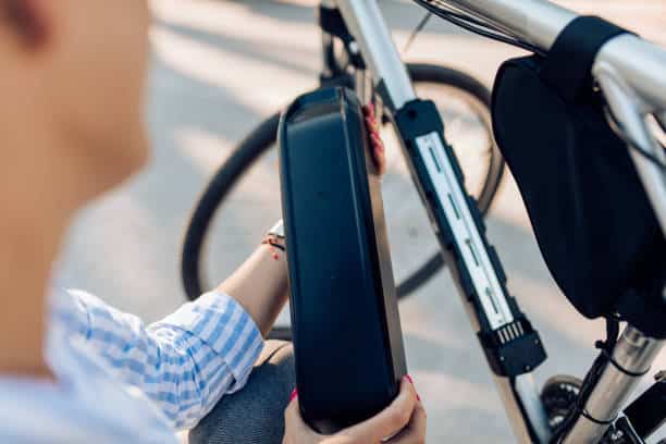 Mid adult woman charging her electric bicycle on her way to work.