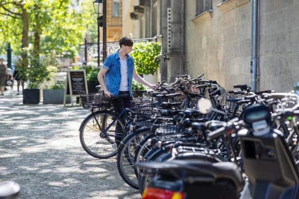 Young man parking his bicycle in cycle stand along the street. Man parking his bike along the road.