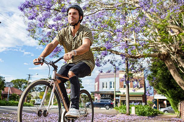 Australian mid adult man riding the bike back home from work on a sunny afternoon in the streets of Sydney.