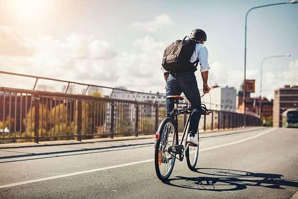 man with backpack riding an e-bike on the road