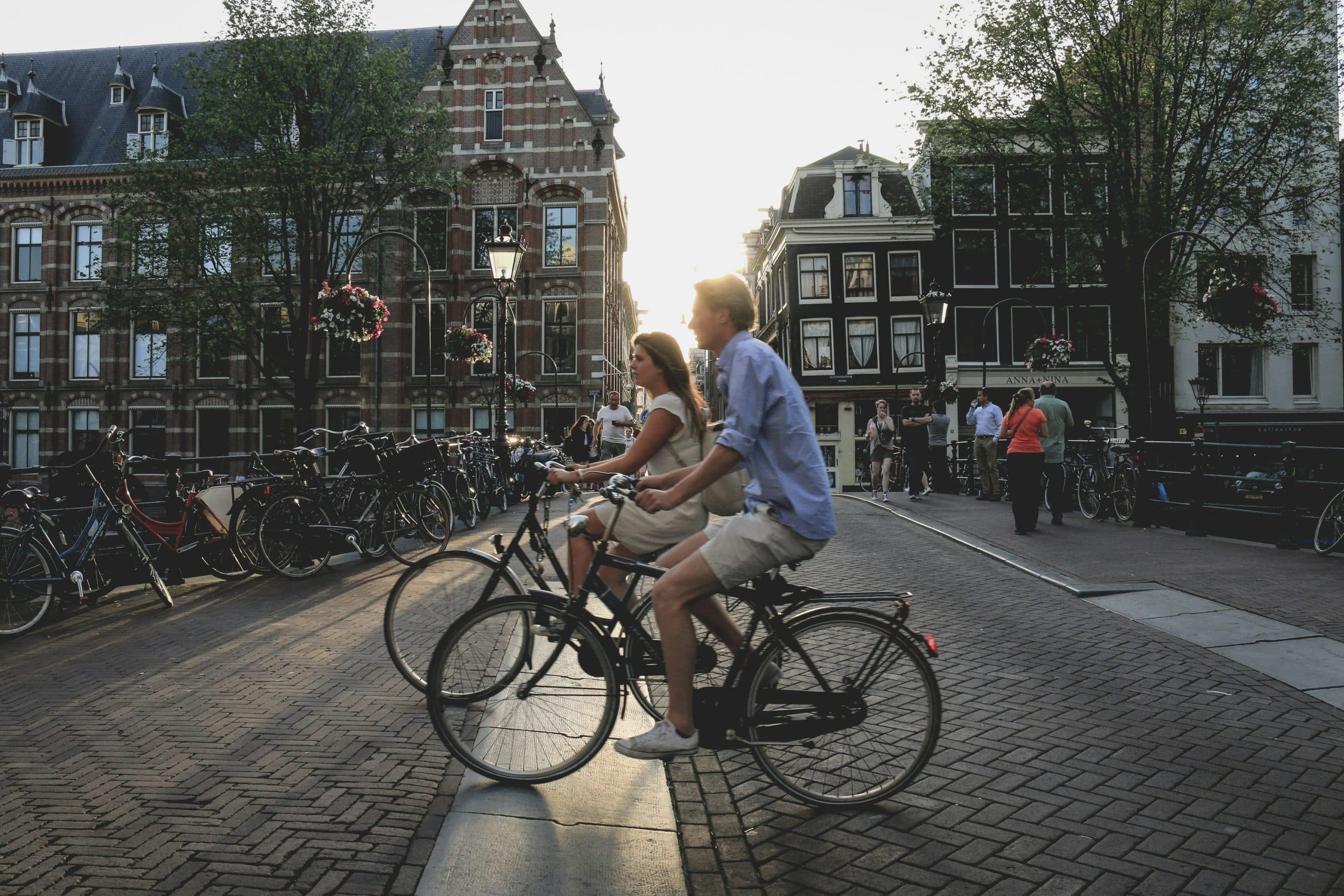 2 people riding e-bikes in the middle of the city